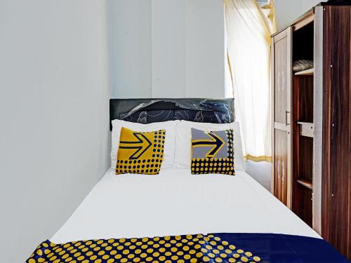 um quarto com uma cama com almofadas amarelas e azuis em SPOT ON 1711 Serayu Sumbersari Residence em Malang