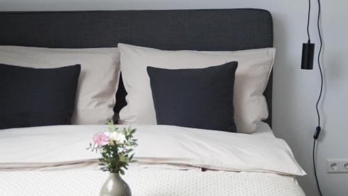 a bed with black and white pillows and a vase with flowers at F&E - gemütliche & zentrumsnahe Unterkunft in Esslingen