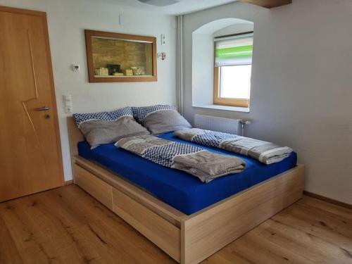 sypialnia z łóżkiem z niebieską pościelą i oknem w obiekcie Schöne Wohnung am Bauernhof 