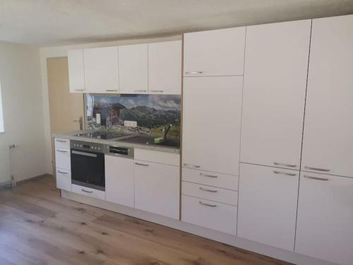 a white kitchen with white cabinets and a stove at Schöne Wohnung am Bauernhof 