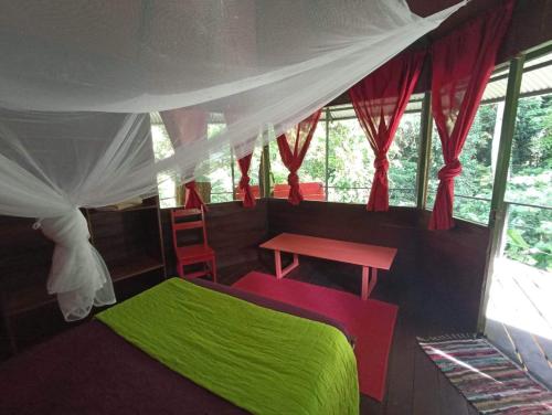a bedroom with a green bed and a table at Finca Valeria Treehouses Glamping in Cocles