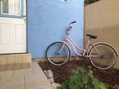 Ovnat的住宿－Beautiful Dead Sea Unit，一辆停在蓝色墙壁旁边的粉红色自行车