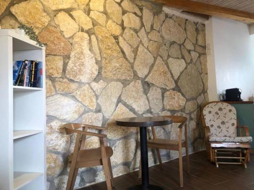 a stone wall with a table and two chairs at Beautiful Dead Sea Unit in Ovnat