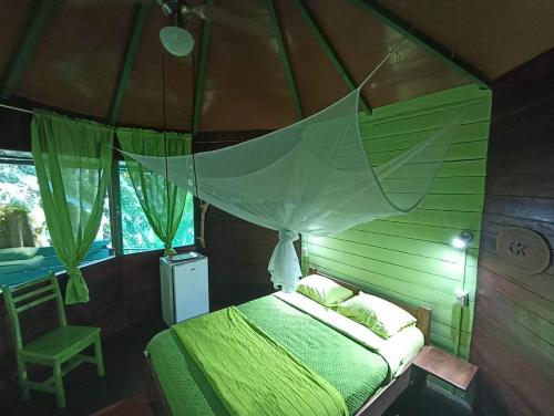a bedroom with a green bed with a canopy at Finca Valeria Treehouses Glamping in Cocles