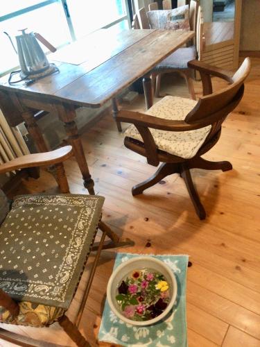 a wooden table with chairs and a bowl of flowers on the floor at Travelers House おーさんてぃん青空舎 in Taketomi