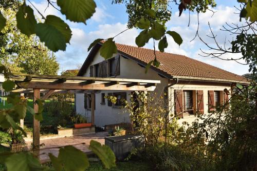 a white house with a wooden pergola at Maison à la campagne entre Nancy et Pont-à-Mousson in Malleloy