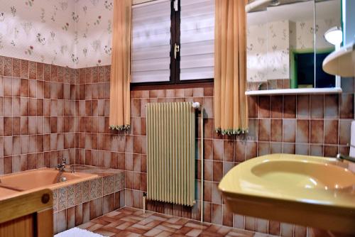 a tiled bathroom with a sink and a tub and a window at Maison à la campagne entre Nancy et Pont-à-Mousson in Malleloy