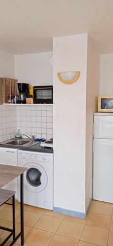 a kitchen with a washing machine and a sink at joli appart les pieds dans l'eau,terrasse et clim in Le Barcarès