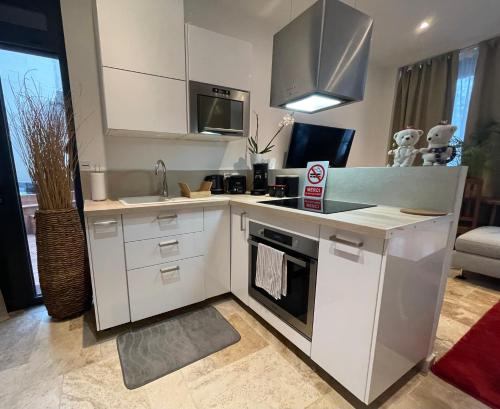 uma cozinha com armários brancos e um forno com placa de fogão em By nuit-parisienne : Superbe appartement avec SPA et terrasse privée em Villemomble