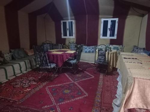 マハミドにあるErg Chegaga Camp & Activitesのテーブル、椅子、ソファが備わる客室です。