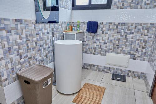 a bathroom with a trash can in a room with tiles at Ravissant appartement 2ch à la plage in Pointe-Noire