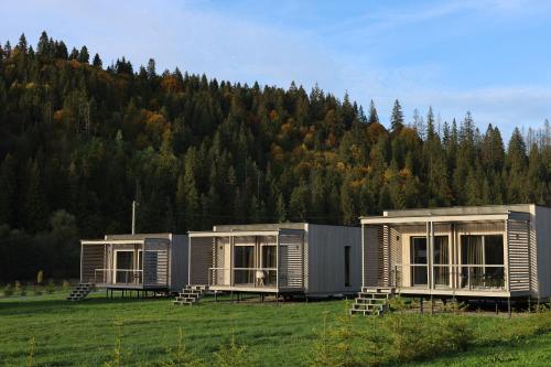 three modular homes in a field with a mountain at River Cottage Complex in Richka