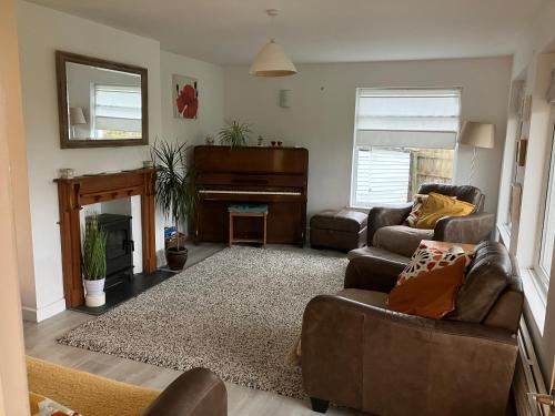 ein Wohnzimmer mit Sofa und Klavier in der Unterkunft Entire house near beaches, footpaths, dog friendly in Barnstaple