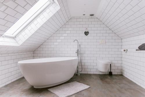a white bathroom with a tub and a toilet at Dunruadh Cottage in Gartocharn