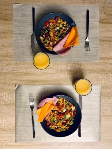 a table with a plate of food and two glasses of orange juice at TOUR de l’europe, en plein centre avec parking. in Mulhouse
