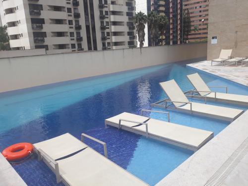 uma piscina com espreguiçadeiras num edifício em Flat sem café da manhã - Cullinan (SHN Brasília) em Brasília