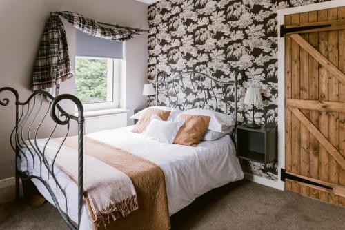 Schlafzimmer mit einem Bett mit Blumentapete in der Unterkunft Dunruadh Cottage in Gartocharn