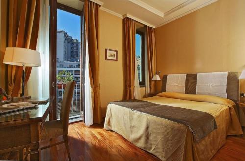 una camera con letto, scrivania e finestra di Palazzo Turchini a Napoli