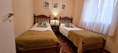 2 camas individuales en una habitación con ventana en Departamento Salta Soho en Salta