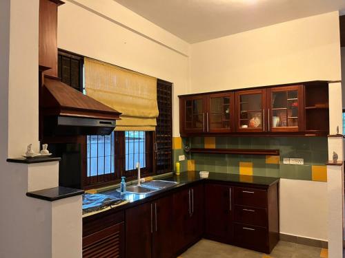 a kitchen with wooden cabinets and a sink and a window at Serene Holiday Home in Pannipitiya