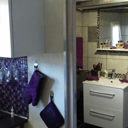 La salle de bains est pourvue d'un lavabo et d'un comptoir avec des serviettes pourpres. dans l'établissement Chalet de charme avec piscine, au Castellet