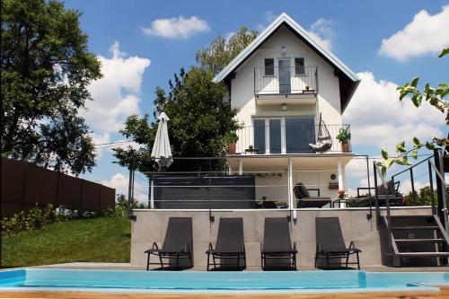 a house with chairs and a pool in front of it at House with hot tub, sauna and swimming pool near Zagreb in Gudci