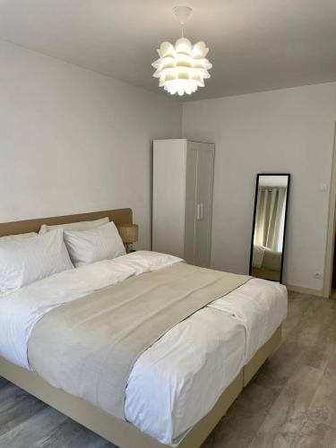 - un grand lit blanc dans une chambre dotée d'un lustre dans l'établissement Cozy Appartement Halles Strasbourg, à Strasbourg