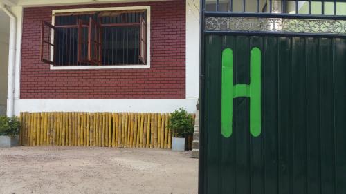 a black gate with a green sign on it next to a building at Hitchhike Backpackers in Mount Lavinia