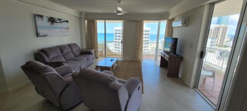 a living room with couches and a tv and a balcony at APR Private SUITES MOROC by the Beach in Gold Coast