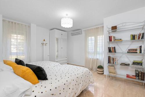 a white bedroom with a bed and a book shelf at El rincón de Rosa in Granada