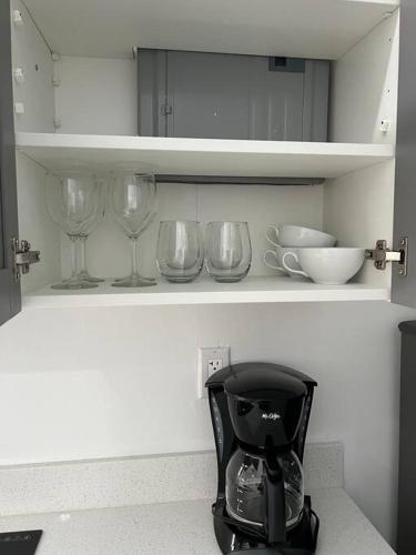 a kitchen shelf with wine glasses and a blender at Stunning Deluxe Studio in Hialeah