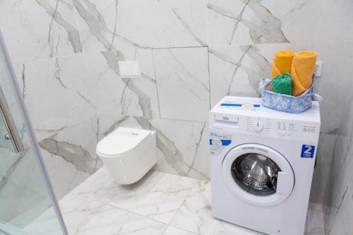 ein Badezimmer mit Waschmaschine und Toilette in der Unterkunft Исы Байзакова 131, новостройка in Pawlodar