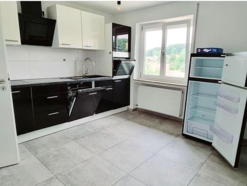 eine Küche mit schwarzen und weißen Geräten und einem Fenster in der Unterkunft Schöne Wohnung auf der Schwäbischen Alb in Münsingen