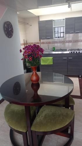 een keuken met een tafel met een vaas met bloemen bij Acogedor y céntrico aparta estudio cerca del aeropuerto in Bogota