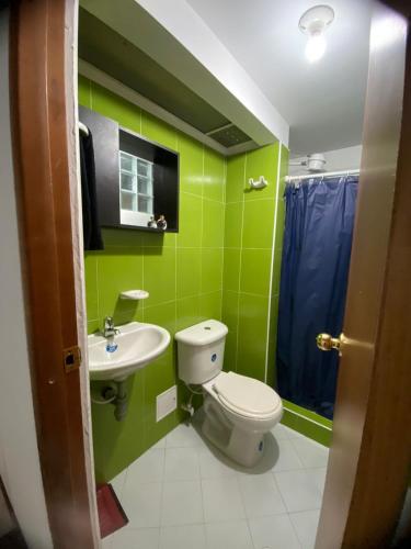 een groene badkamer met een toilet en een wastafel bij Acogedor y céntrico aparta estudio cerca del aeropuerto in Bogota