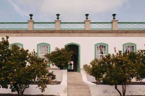 un edificio blanco con techo verde y escaleras en Hotel Emblemático La Casa de los Naranjos en Haría