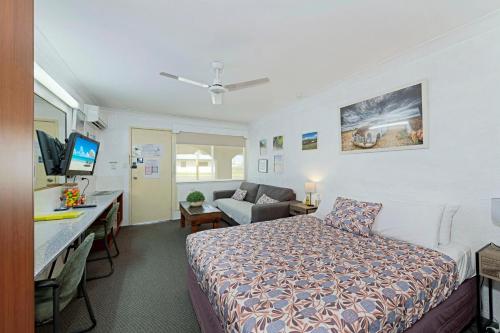 a hotel room with a bed and a desk at Bundaberg Coral Villa Motor Inn in Bundaberg