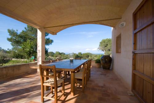 una sala da pranzo all'aperto con tavolo e sedie in legno di Sa Paret Nova a La Savina