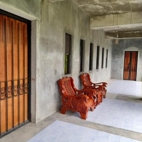 two wooden chairs sitting on the side of a building at DUMAHOSTEL in Daro