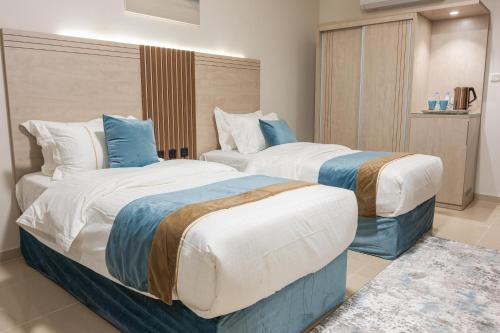 Dos camas en una habitación de hotel con azul y blanco en ابات بارك Abat Park en Al Baha