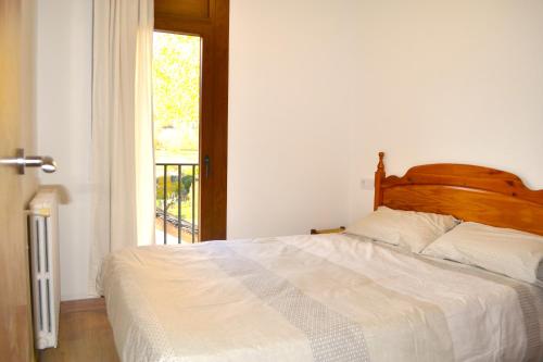 a bedroom with a bed with a wooden headboard and a window at Apartament familiar amb vistes i cèntric by RURAL D'ÀNEU in Esterri d'Àneu