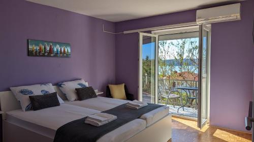 a bedroom with a large bed with purple walls at Apartments Kety - Central heating in Crikvenica