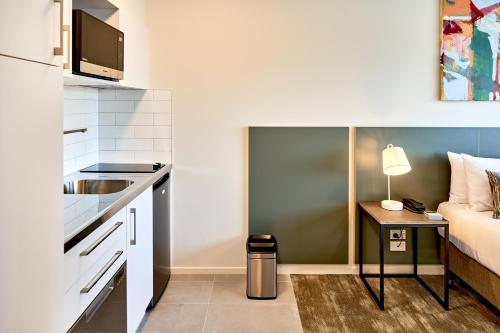 a small kitchen with a sink and a bed at Sojourn Apartment Hotel - Ghuznee in Wellington