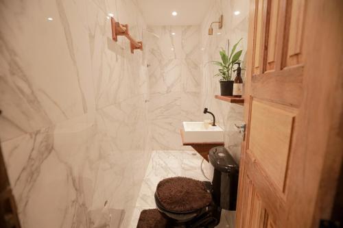 bagno con lavandino e doccia con pareti in marmo di Apartamentos Prana a Itacaré