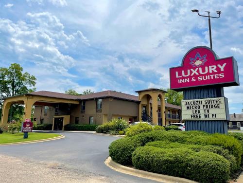 um hotel com um sinal para estalagem e suites aluxuárias em Luxury Inn & Suites em Selma