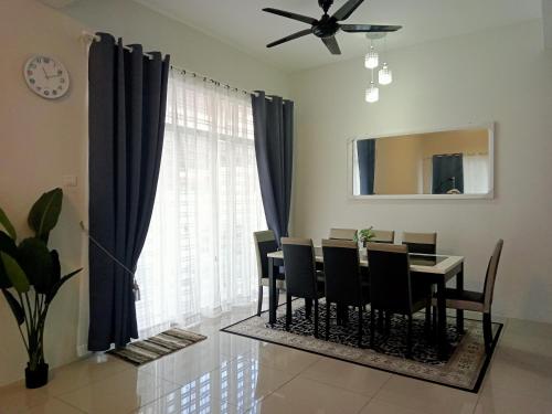 a dining room with a table and chairs and a clock at Ana Homestay D'Airport in Melaka