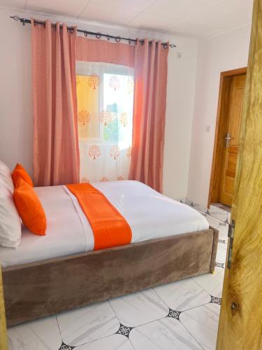 een bed met oranje en witte lakens in een kamer bij Studio meublé Cosy in Douala