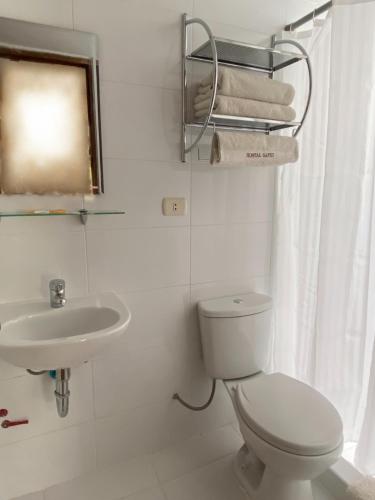 a white bathroom with a toilet and a sink at Hostal Saphi - Excelente ubicación in Cusco