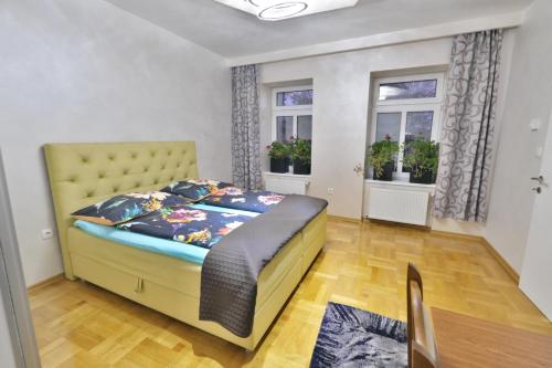 a bedroom with a yellow bed and two windows at Lux Apartments Prestige in Vienna