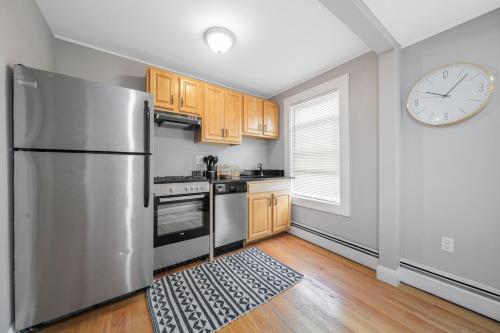 a kitchen with a stainless steel refrigerator and a clock at Easy Commute South Boston 4BR 1BH Apt in Boston